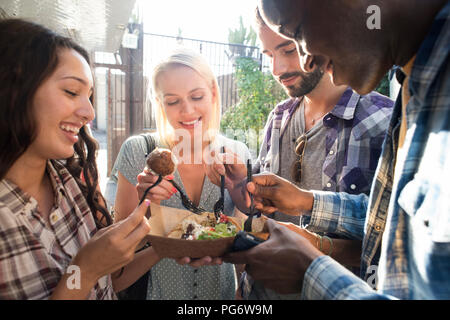 Happy friends sharing takeaway food outdoors Stock Photo
