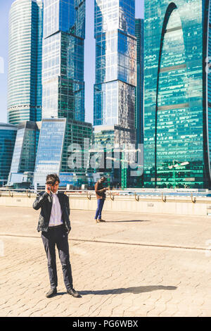 Russia, Moscow, two businessmen using cell phones in the city Stock Photo