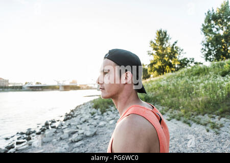 Young man wearing baseball cap looking at the river Stock Photo