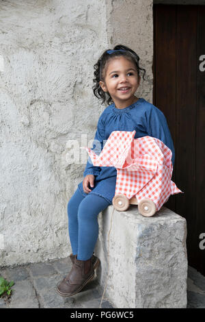 Little girl sitting on wall, origami elephant with rolls Stock Photo