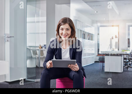 Portrait of smiling young businesswoman using tablet in office Stock Photo