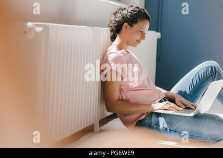 Woman sitting on ground, using laptop Stock Photo