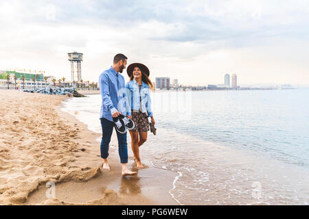 Spain, Barcelona, couple walking barefoot on the beach Stock Photo