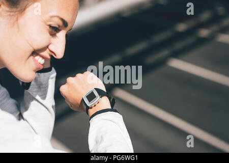 Smiling sportive young woman outdoors with watch Stock Photo