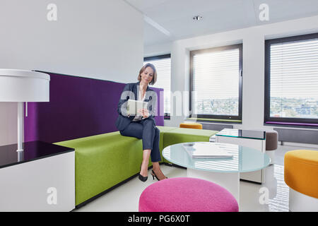 Businesswoman using tablet in office lounge Stock Photo