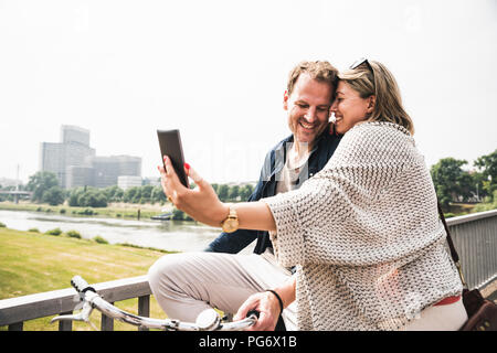 Happy couple taking a selfie on a bridge Stock Photo