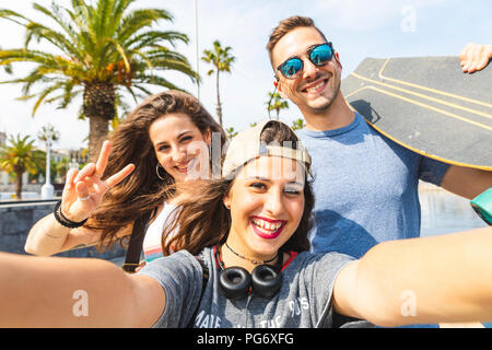 selfie of three happy friends with skateboard
