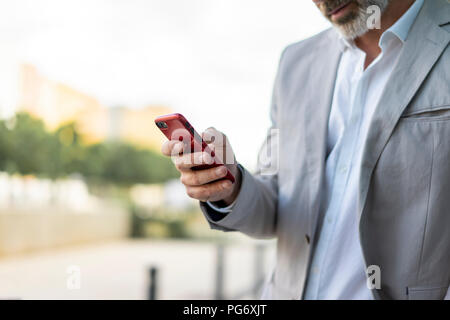Businessman using smartphone outdoors, partial view Stock Photo