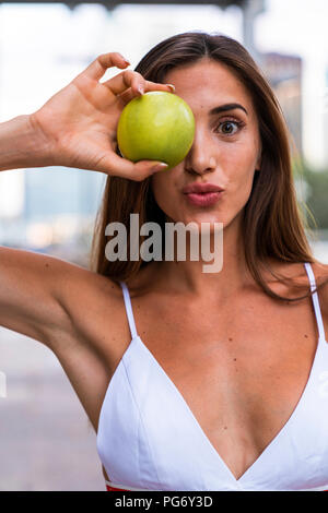Portrait of attractive young woman wearing sports bra holding an apple Stock Photo