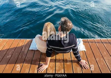 Mature couple sitting on jetty, relaxing at the sea Stock Photo