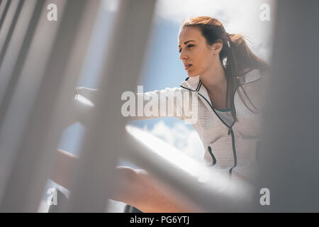 Sportive young woman stretching at railing Stock Photo