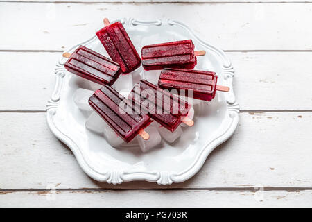 Cherry ice lollies on ice cubes and plate Stock Photo
