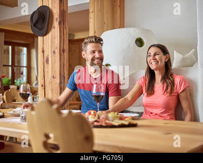 Happy couple having a snack in an alpine cabin Stock Photo