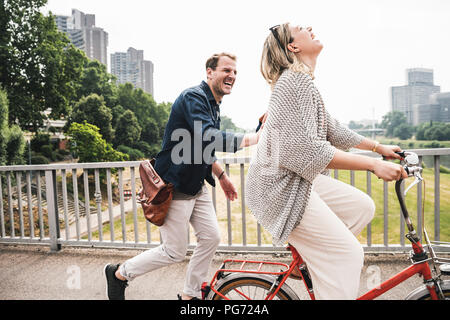 Happy couple crossing a bridge with bicycle and by foot Stock Photo