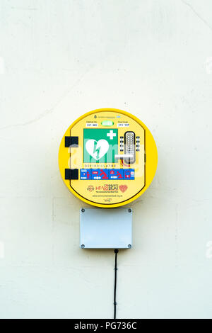 Defibrillator in round yellow box mounted on white wall Stock Photo