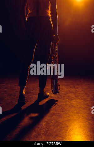 cropped shot of musician holding saxophone on stage Stock Photo