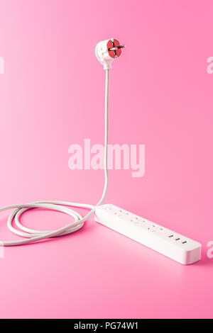 close-up view of white socket outlet and plug isolated on pink Stock Photo