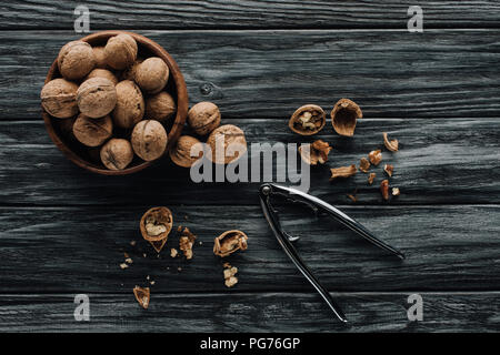 walnuts in wooden bowl and nutcracker on dark wooden background Stock Photo