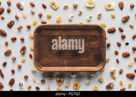 flat lay with dried fruits and nuts with wooden plate in center isolated on white background Stock Photo