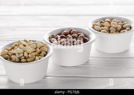 delicious nuts in ceramic bowls on white wooden tabletop Stock Photo