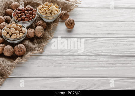 Assorted nuts in glass bowls on white wooden tabletop Stock Photo