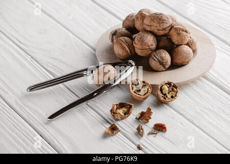 walnuts with metal nutcracker on wooden background Stock Photo