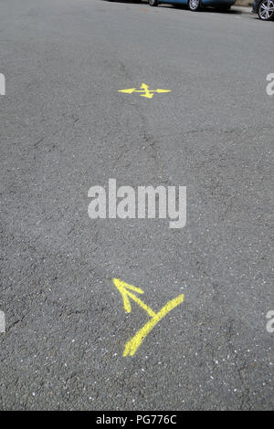 Yellow painted arrows painted on tarmac road surface Stock Photo
