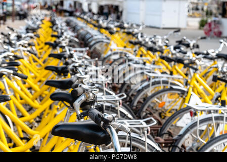 Yellow bicycle rental station on city street. Narrow depth of field Stock Photo