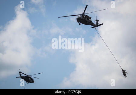 U.S. Air Force Tactical Air Control Party Airmen with the 227th Air Support Operations Squadron hang underneath a 1-150th Assault Helicopter Battalion UH-60L Black Hawk helicopter during a special extraction system demonstration during the Thunder over the Boardwalk Air Show in Atlantic City, N.J., Aug. 22, 2018. (U.S. Air National Guard photo by Master Sgt. Matt Hecht) Stock Photo