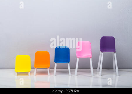 Increasing Size Of Colorful Chairs Arranged In A Row Stock Photo