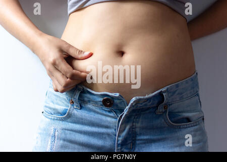 woman with overweight abdomen. hand holding excessive fat belly. Stock Photo