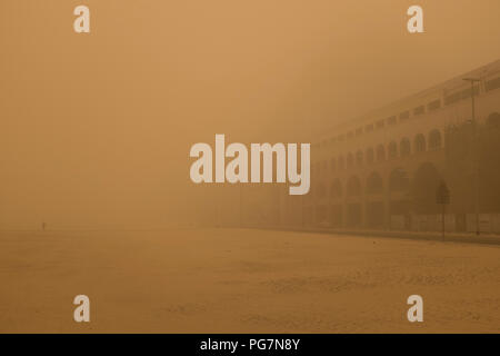 Man walking in the Al Barsha district of Dubai, United Arab Emirates, during a sandstorm, with the Mall of the Emirates barely visible Stock Photo