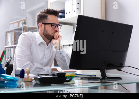 Young Businessman Looking At Computer Screen In Office Stock Photo