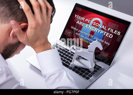 Close-up Of A Sad Businessman With Laptop Screen Showing Personal Files Encrypted Text Stock Photo