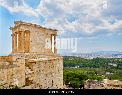 The Temple of Athena Nike, ancient Ionic temple depicting goddess Athena, at the Athenian Acropolis, with the city of Athens in background. Athens, At Stock Photo