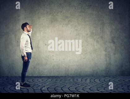 Side view of stylish businessman looking away planning future and doing forecast on gray background Stock Photo