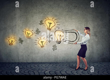 Business woman attracts bright ideas light bulbs with a big magnet Stock Photo