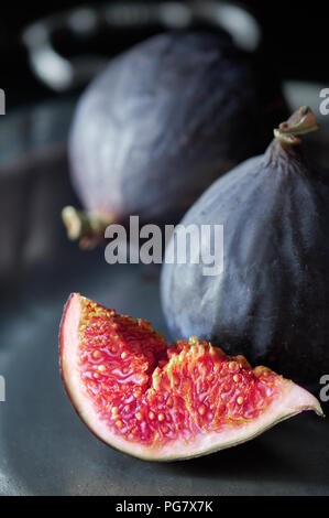 Close-up on a sliced quarter of fresh black fig on a vintage metal plate, side view Stock Photo