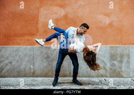 Carefree couple in love in front of a wall outdoors Stock Photo