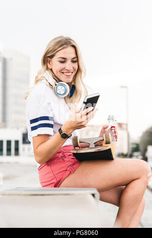 Young woman with skateboard, listening music Stock Photo