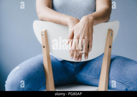 Hands of a woman sitting on a chair Stock Photo