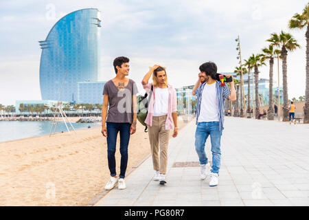 Spain, Barcelona, three friends walking on beach promenade Stock Photo