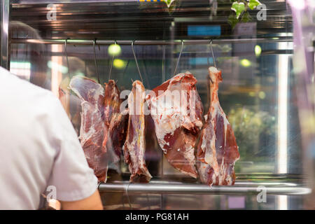 Serrano ham hanging on hooks in market stall Stock Photo