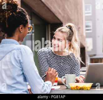 Young colleagues sitting outdoors, working together, having lunch Stock Photo