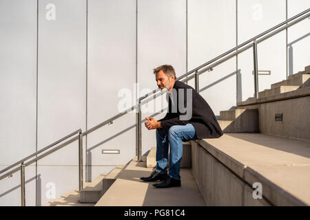 Businessman sitting on steps outdoors relaxing Stock Photo