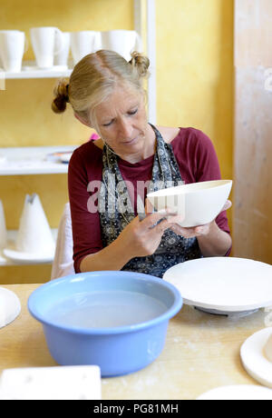 Woman working on bowl in porcelain workshop Stock Photo