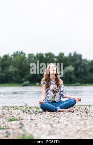 Woman practicing yoga at the riverside Stock Photo