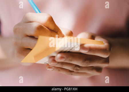 Woman writing with pen on adhesive notes Stock Photo