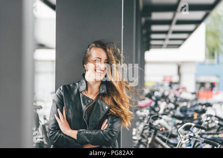 Portrait of happy young woman at bicycle parking station in the city Stock Photo