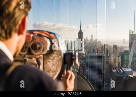USA, New York City, man looking through coin-operated binoculars on Rockefeller Center observation deck Stock Photo